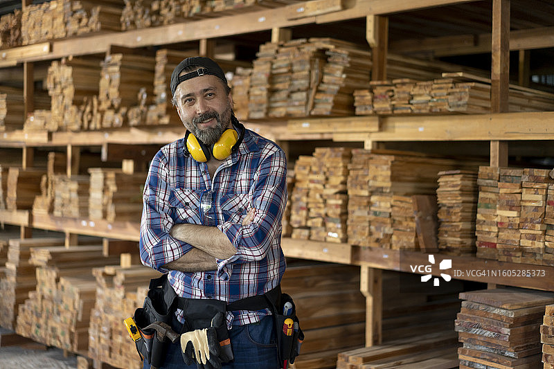 在工作室里堆满了木头的、非常开心的友好的木匠图片素材