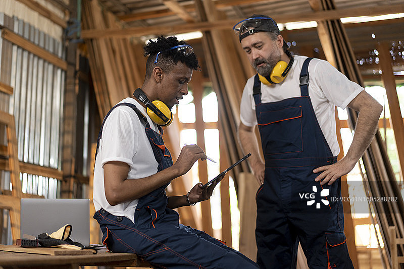 在木工车间使用数字平板电脑的年轻手工工人图片素材