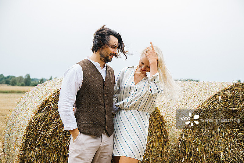 勤劳的农民和快乐的金发伙伴在两个干草捆旁分享美好时光图片素材