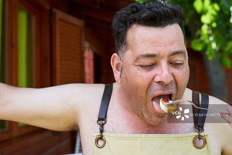 吃着番茄酱和蛋黄酱的马铃薯的白人中年男人，餐饮概念图片素材