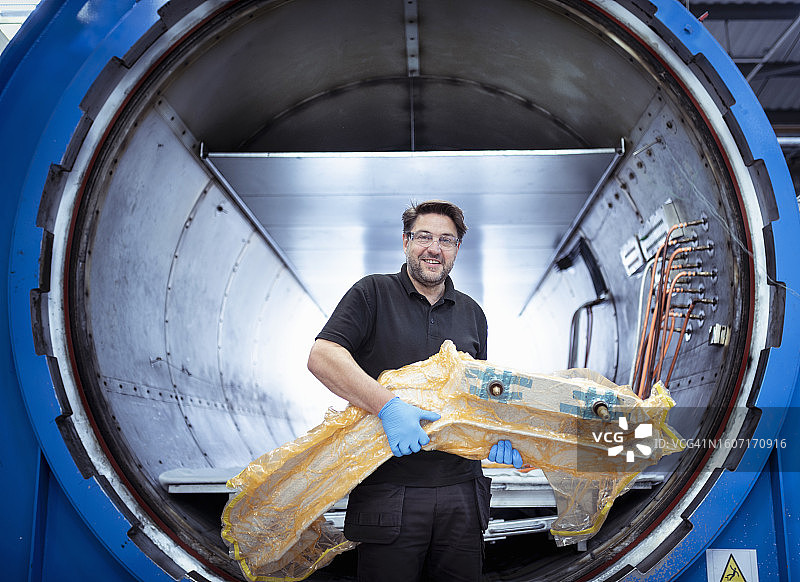 汽车零件工厂：工人操作碳纤维汽车零件图片素材