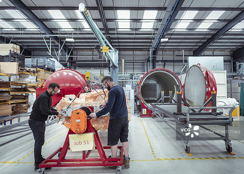 汽车零件工厂中准备进入高压灭菌器的碳纤维部件的工人图片素材