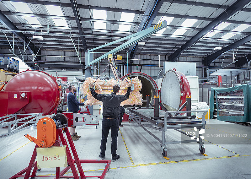 汽车零件厂的工人们将碳纤维部件吊入高压釜图片素材