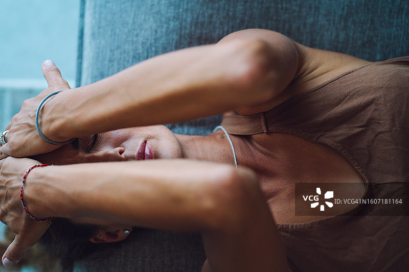 寻求慰藉：女子俯卧床上面部被手遮挡图片素材