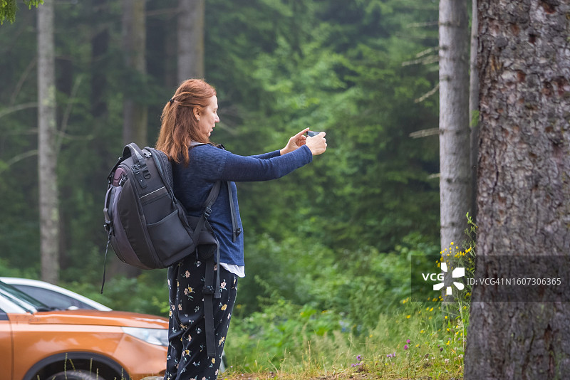 在森林里使用智能手机的中年妇女图片素材