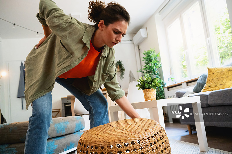 年轻女人在家做家务时感到背痛图片素材