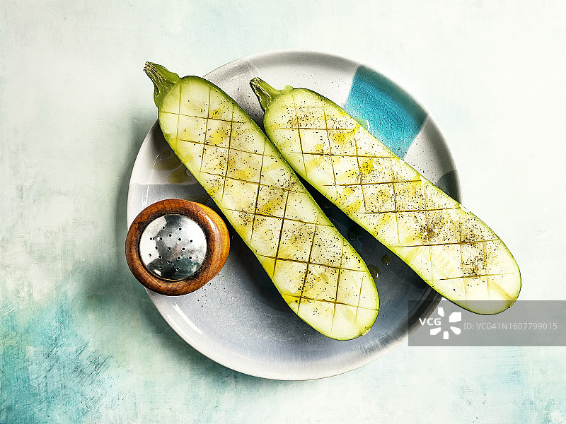 蓝色风化背景盘子上的半个生西葫芦图片素材