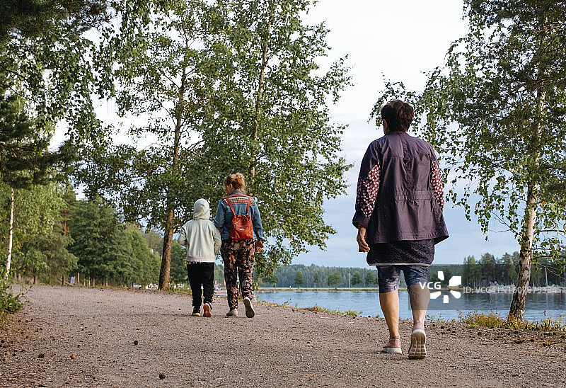高加索人家庭在湖边散步，一位老妇人、一位8岁女孩和一位年轻女子在度假时共度时光图片素材