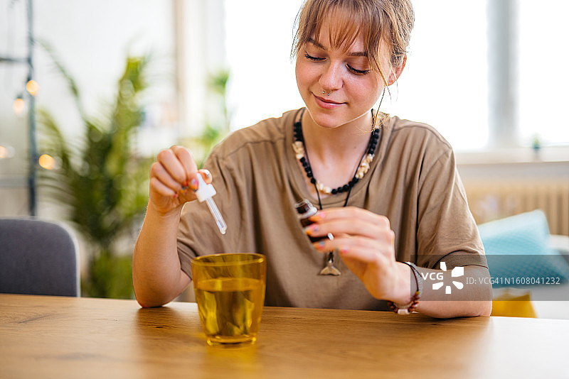 年轻女人在一杯水中滴药图片素材