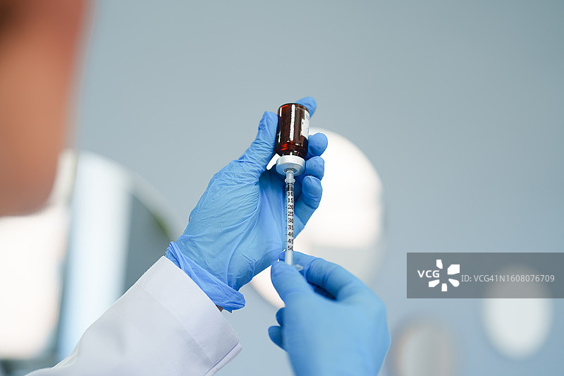 戴蓝色手套的护士正在抽取药液图片素材