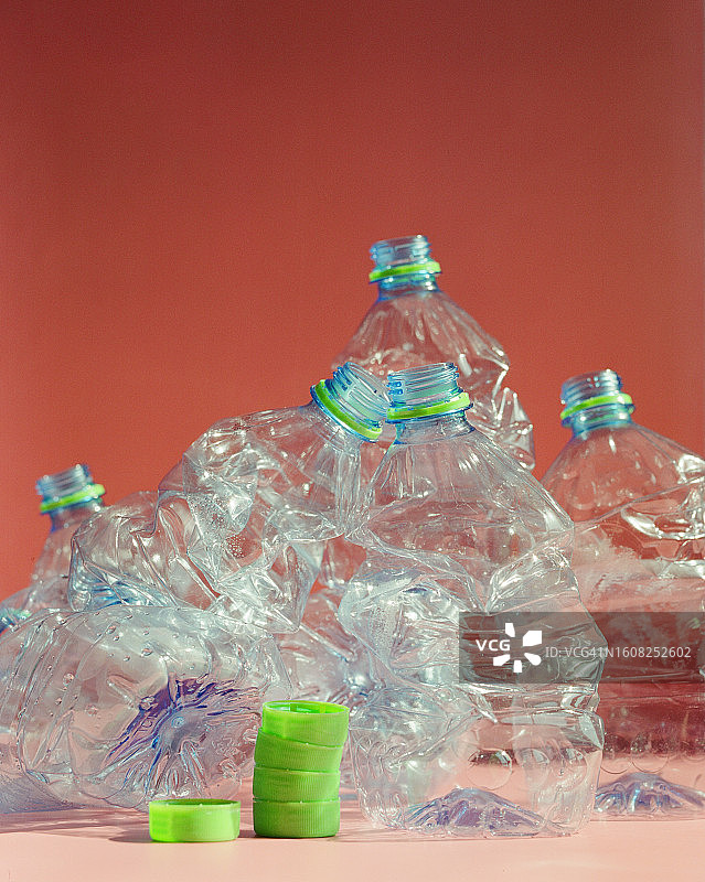 粉色背景上的一堆空水瓶和瓶盖图片素材