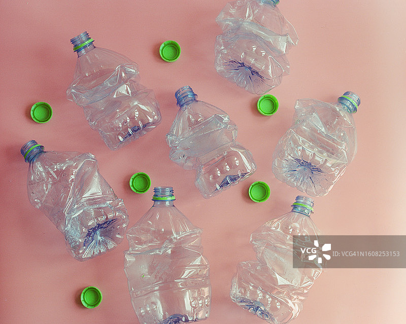 粉色背景上的空矿泉水瓶和瓶盖图片素材