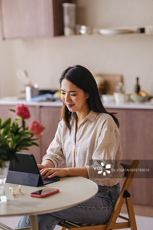 快乐的亚洲女商人居家使用平板电脑工作图片素材
