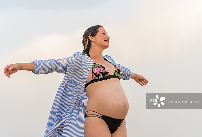 孕妇张开双臂站在蓝天下图片素材