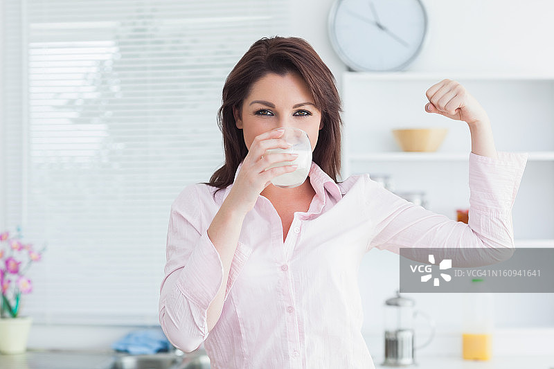 女人喝牛奶并展示肌肉图片素材