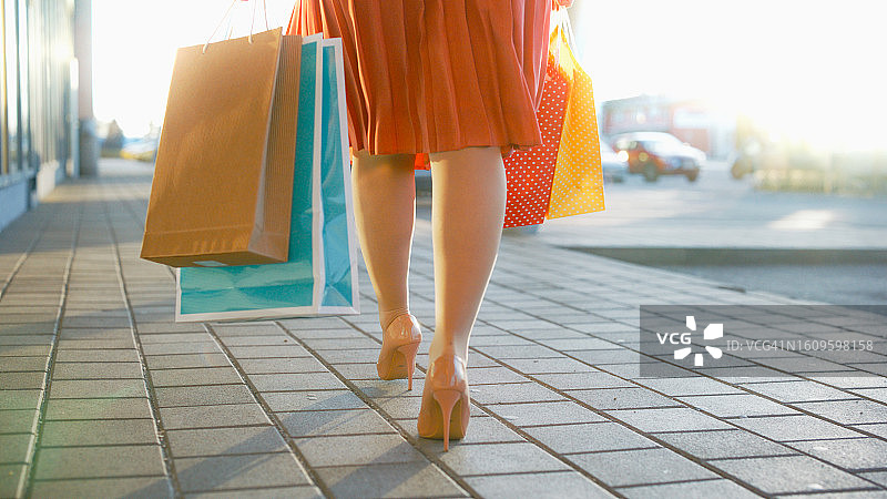 女子提着购物袋在人行道上行走的低角度照片图片素材