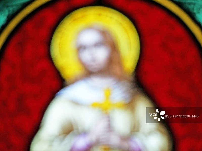 法国巴黎，彩色老旧的彩色玻璃窗上带有十字架的宗教人物的模糊照片图片素材