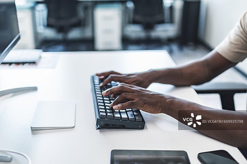 在办公室工作的非洲男人在键盘上打字的手部特写图片素材