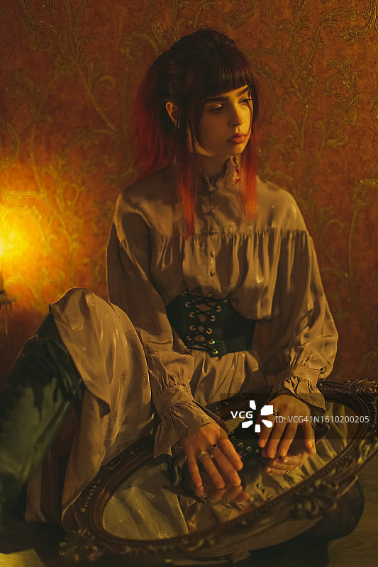 身穿紧身胸衣的红发哥特女孩。烛光图片素材