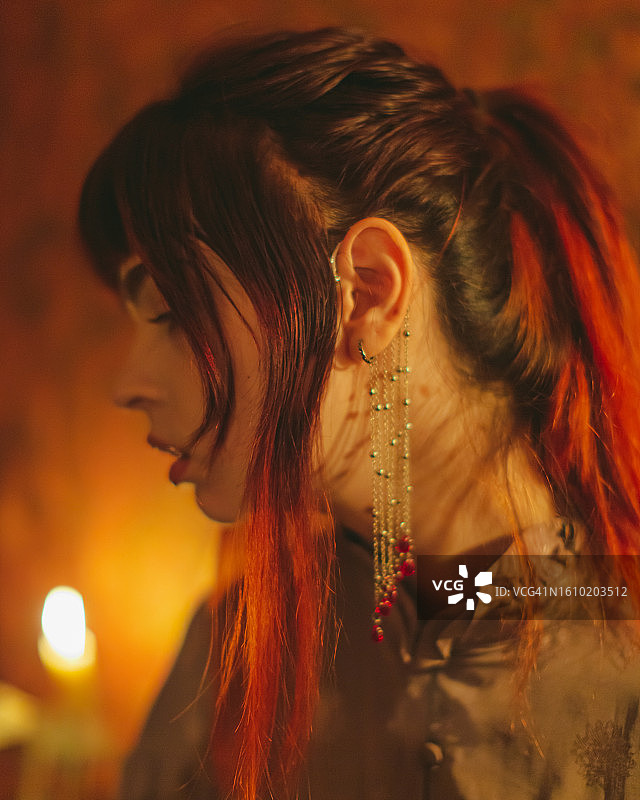 身穿紧身胸衣的红发哥特女孩。烛光图片素材