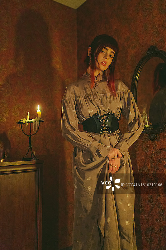 身穿紧身胸衣的红发哥特女孩。烛光图片素材