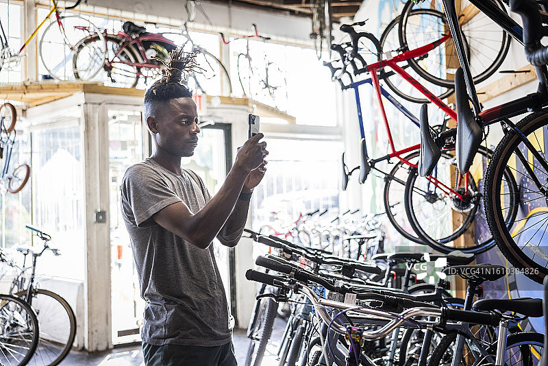 自行车店主用手机记录库存图片素材