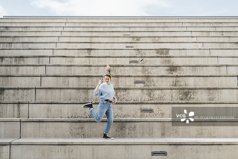戴着耳机在城市楼梯上跳舞的年轻女子图片素材