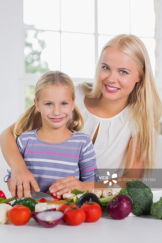 微笑的母亲教孩子切菜图片素材