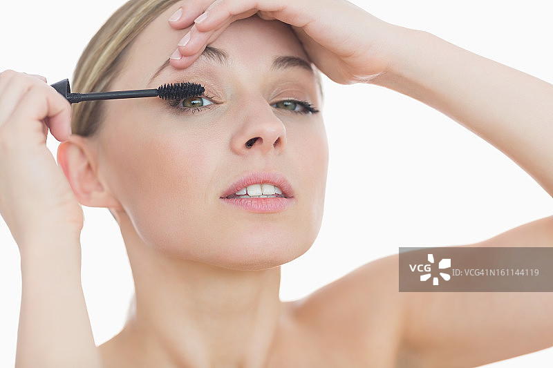 年轻女子往眼睛上涂睫毛膏的特写肖像图片素材