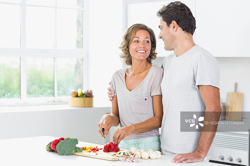 丈夫拥抱正在准备蔬菜的妻子图片素材