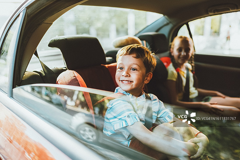 坐在汽车安全座椅上对着镜头微笑的兄妹图片素材