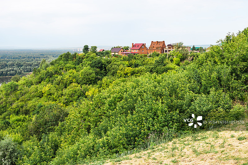 美丽的欧洲乡村夏景：乡村房屋背景下的绿色森林图片素材