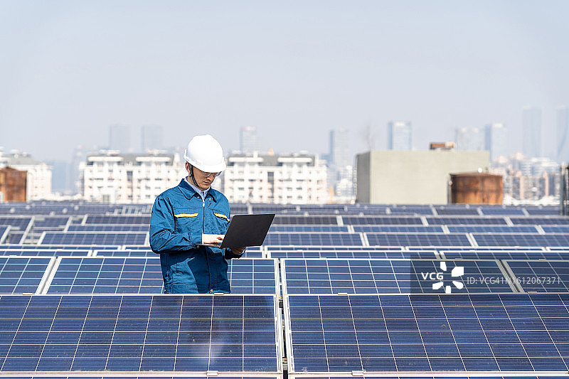 在太阳能发电站工作的男维修工程师，携带笔记本电脑图片素材