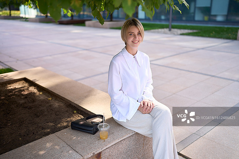 身着休闲装坐在石凳上的年轻自信的女人肖像。图片素材