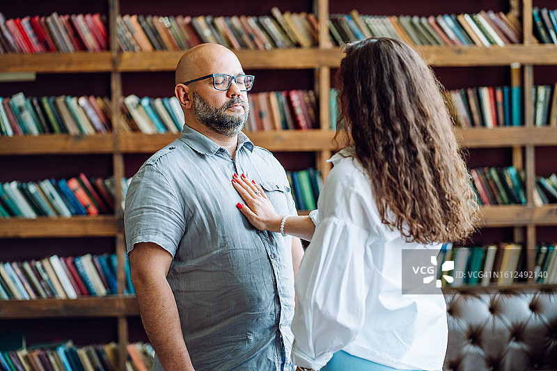 社交恐惧症与治疗。医生办公室里，光头络腮胡男子闭着眼睛，戴着眼镜，女人的手放在他的胸前。女人后视，焦点在男人身上图片素材