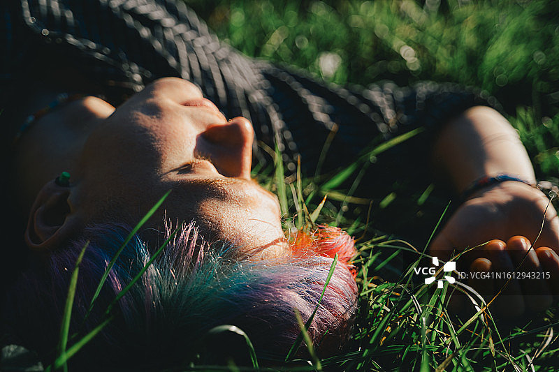 草地上放松的时尚彩色发型男子图片素材