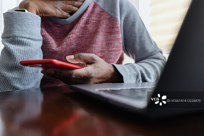 女人在使用笔记本电脑时使用智能手机图片素材