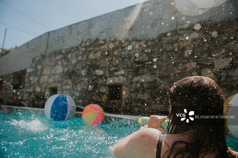 女人在室外游泳池用水枪喷水图片素材
