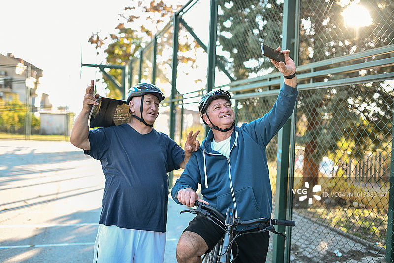 年长的男人们在社交媒体上发布户外爱好自拍照——骑自行车和滑板图片素材