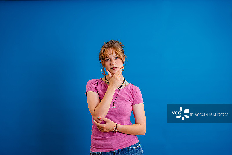 沉思的年轻女子，蓝色背景图片素材