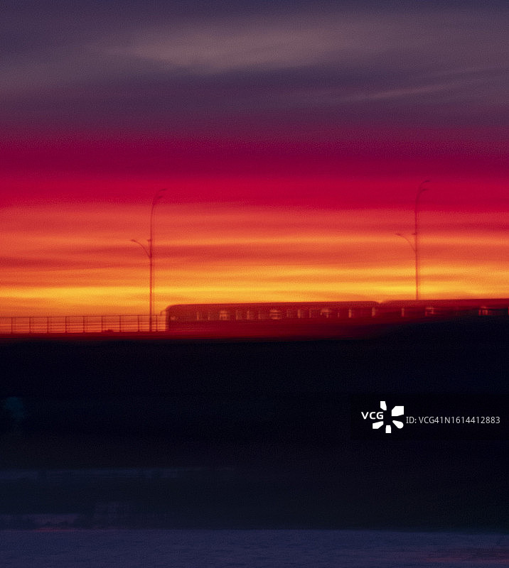 地铁列车穿梭于橙红色夕阳中图片素材