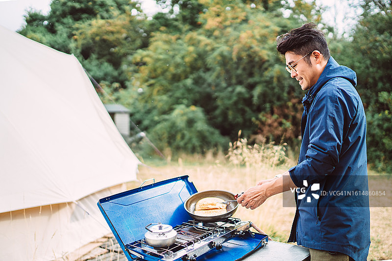 在露营地用炉子做饭的年轻亚洲男子图片素材