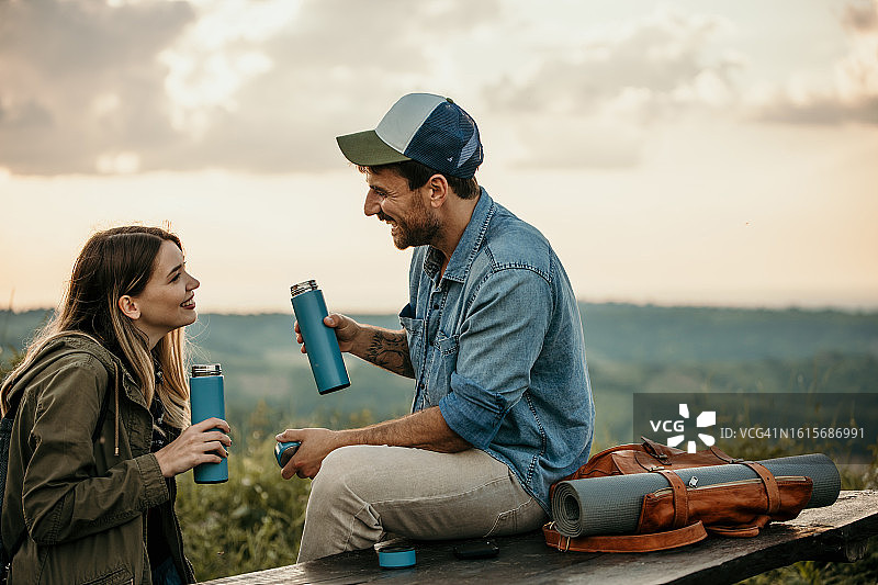 一对情侣在长椅上亲密地坐着，喝水并珍惜彼此的时光图片素材