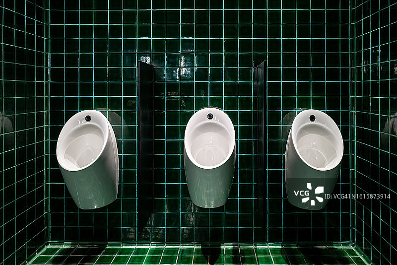 浴室里的陶瓷小便池，绿色瓷砖图片素材