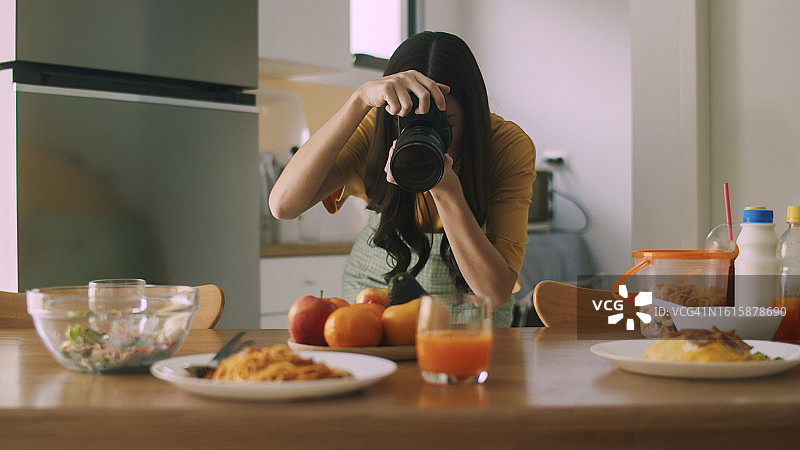 年轻的亚洲女人在家中厨房用相机拍摄意大利面图片素材