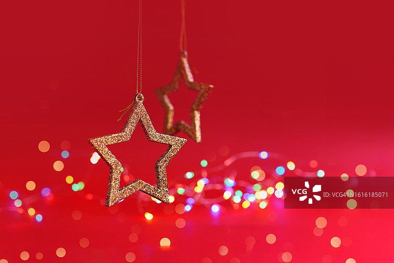 红色背景上的圣诞树装饰品，留白。金色星星和银色灯光，正面视角图片素材