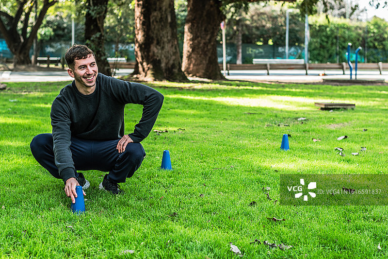 年轻男人在公园准备运动训练锥图片素材