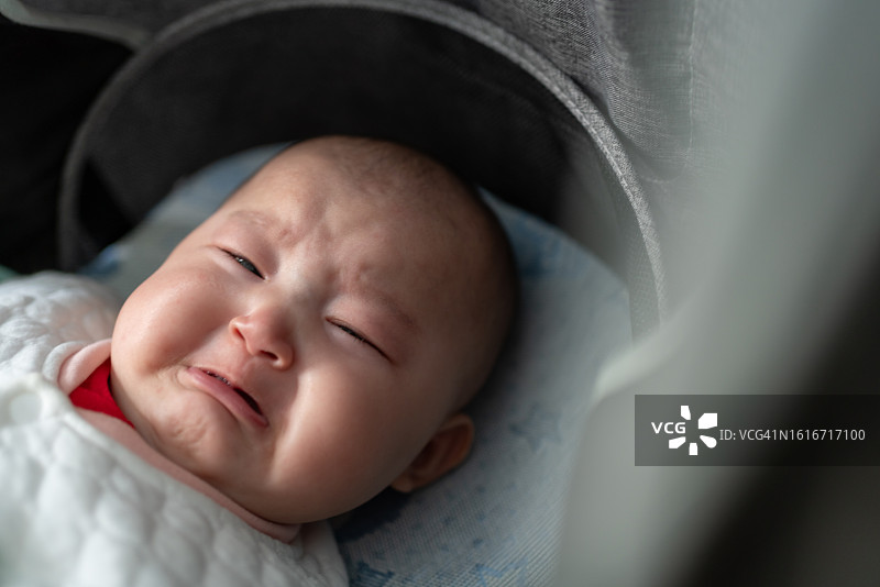 亚洲女婴躺在婴儿车里哭泣图片素材