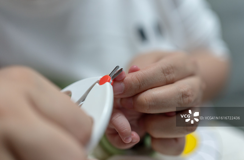 年轻的亚洲母亲给婴儿剪指甲图片素材