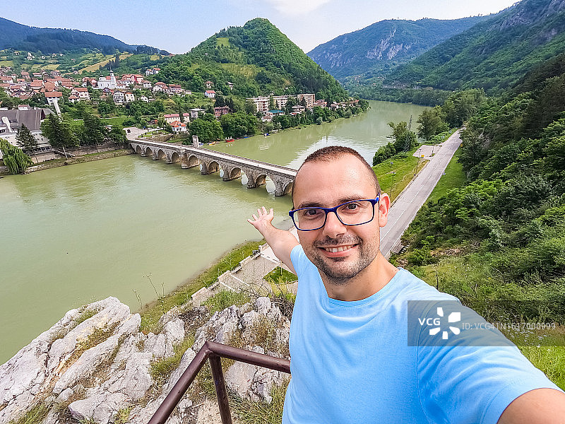 男人在智能手机上进行视频通话，背景是维谢格拉德的古老桥梁图片素材
